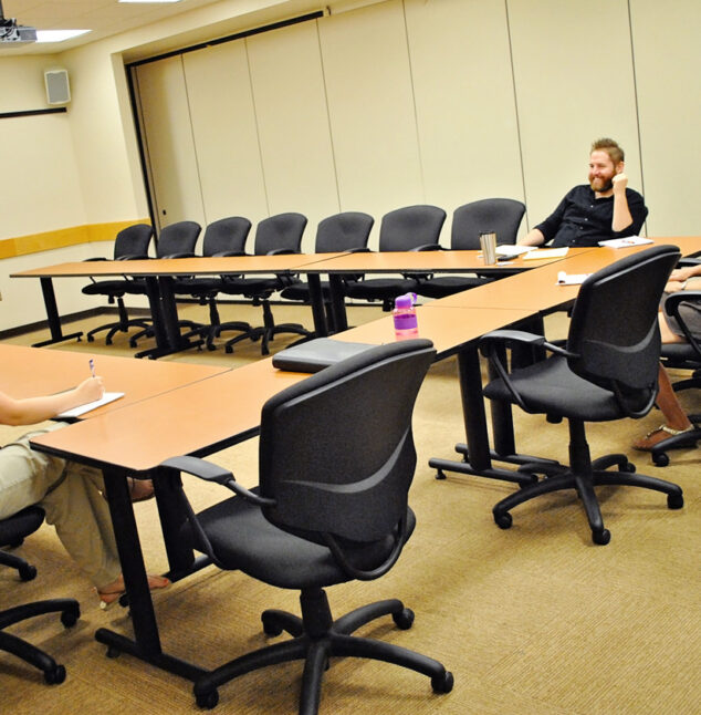 A meeting room with three people discussing business.
