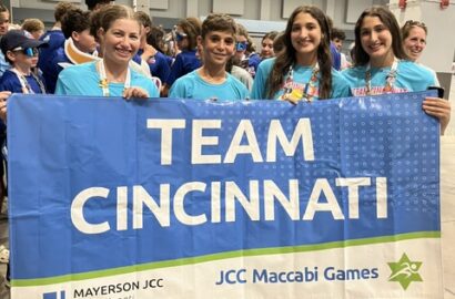 Kids smiling and holding a flag that says Team Cincinnati