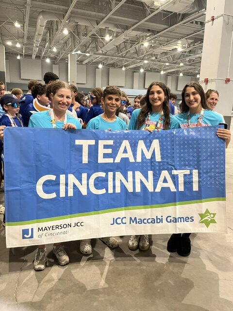 Kids smiling and holding a flag that says Team Cincinnati