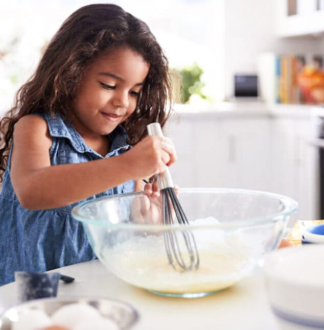 A girl using a mixing bowl.