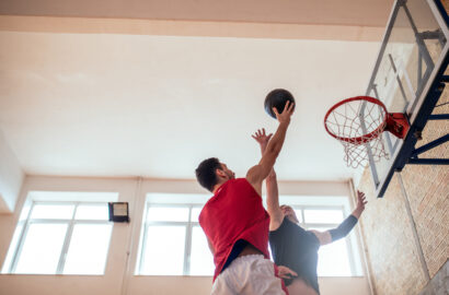 Two young man playing basketball indoors.
