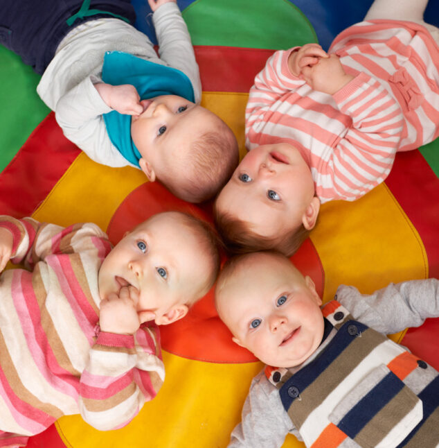 Overhead View Of Babies Lying On Mat At Playgroup.