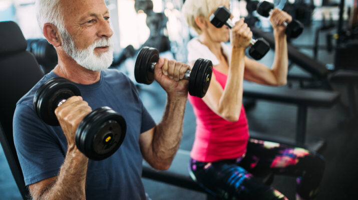 Senior fit couple exercising in gym to stay healthy.