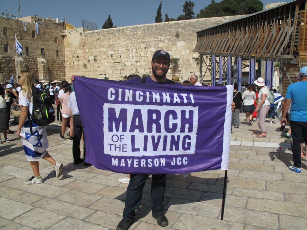 Man holding Cincinnati March of the Living Mayerson JCC flag