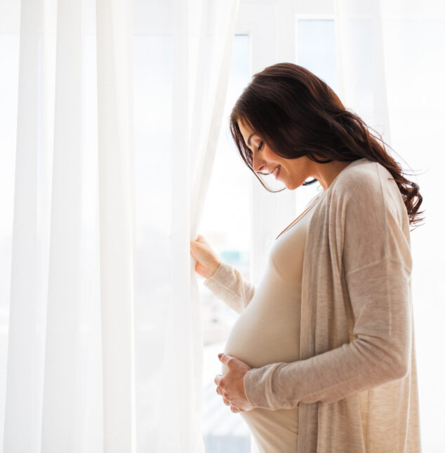 Pregnant woman looking out window