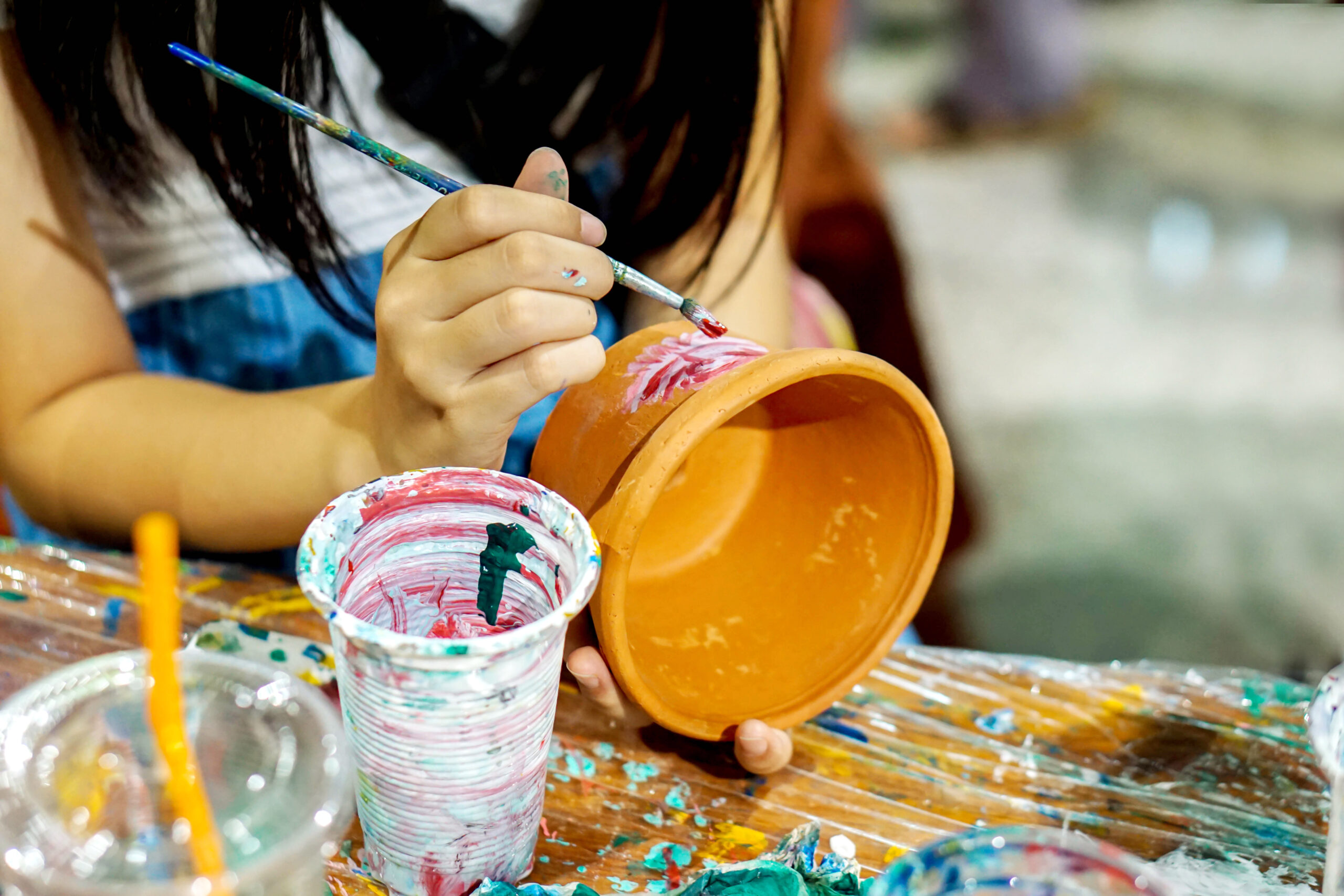 Young girl painting pottery