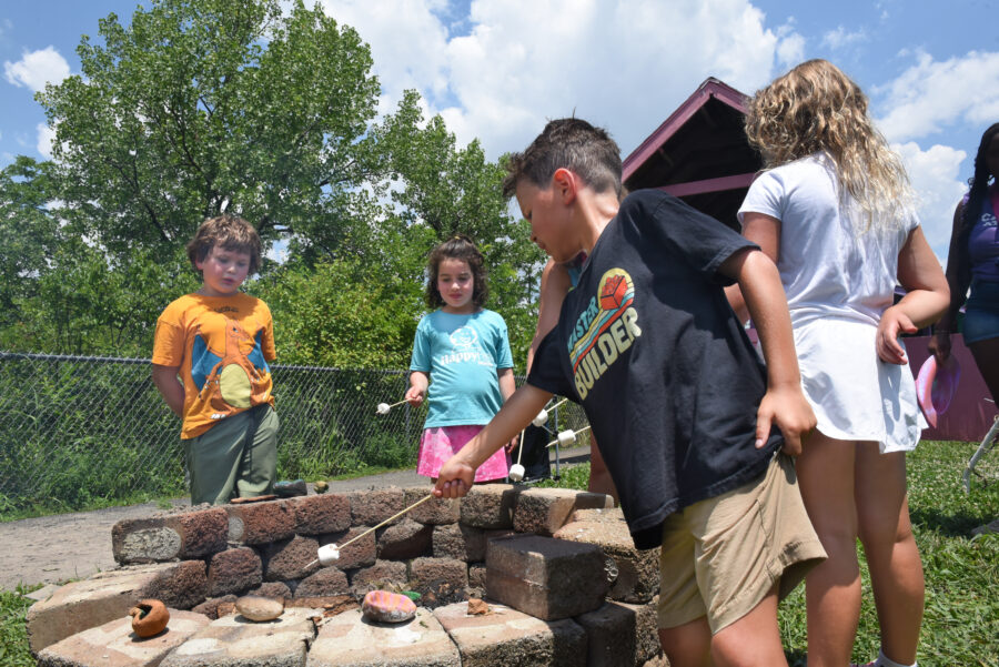 Kids gathered around a campfire roasting marshmallows