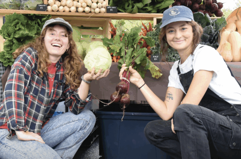 Two people posing in front of their produce stand