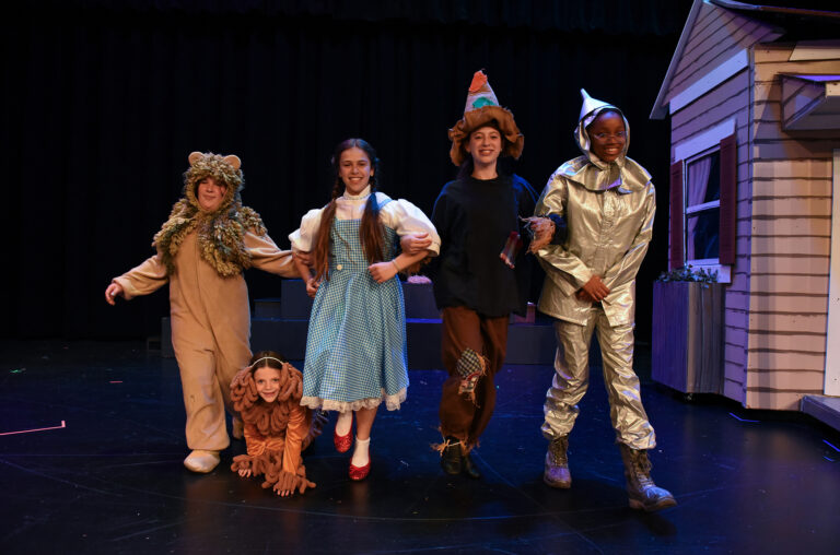 The lion, Dorothy, scarecrow, and tin man walking in the Wizard of Oz