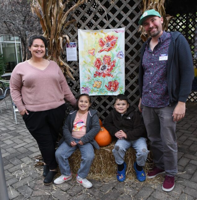 Two people posing in front of their artwork at Under One Roof